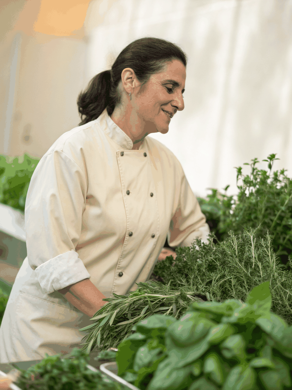 Chef Lucia Bianchi selecting fresh herbs for the menu